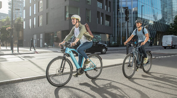a man and woman riding eBikes down a city roadway