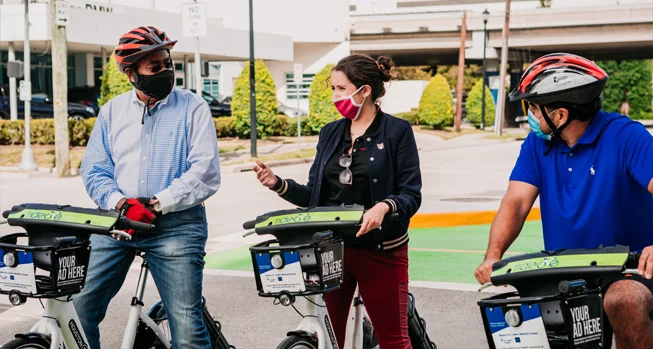 Three people wearing masks riding rental eBikes