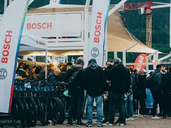 A crowd gathers at pavilions and booths with the Bosch logo; eBikes are lined up next to a Bosch flag.