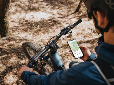 a rider on an eMTB consults navigation on his mobile app