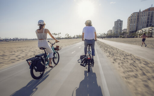 Two ebike riders enjoy the beach views on a bike path