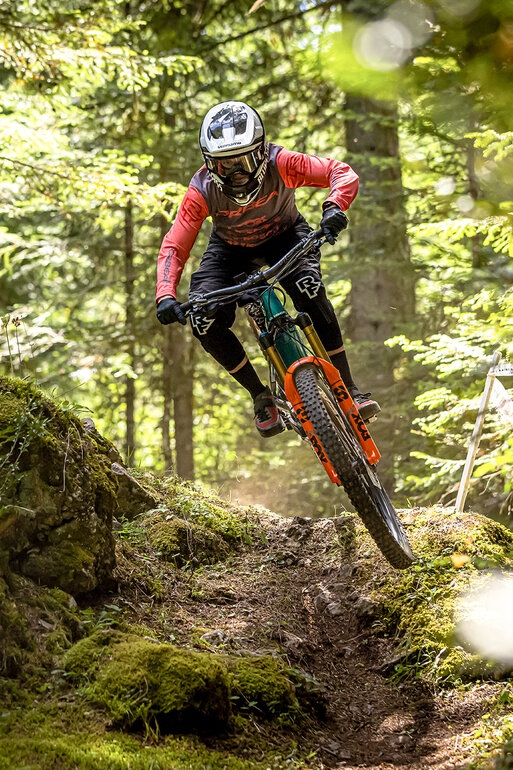 An [eMTB] rider speeds along a trail through the forest.