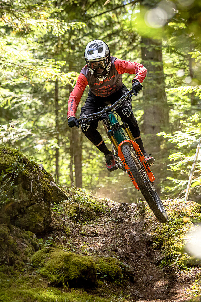 An [eMTB] rider speeds along a trail through the forest.
