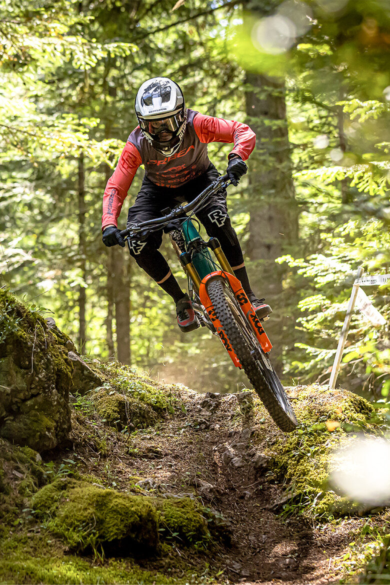 Ein eMTB-Fahrer fährt schnell einen Trail durch den Wald entlang.