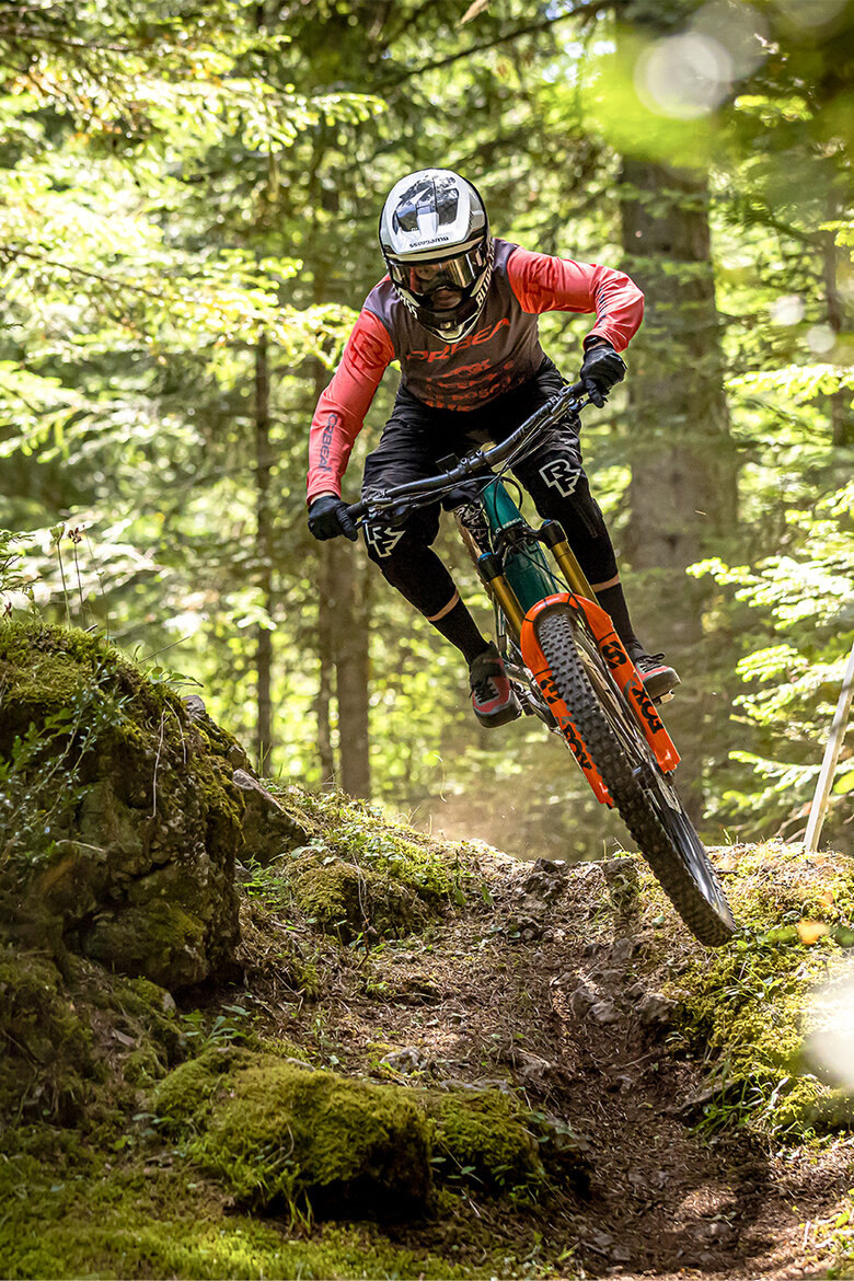 Ein eMTB-Fahrer fährt schnell einen Trail durch den Wald entlang.