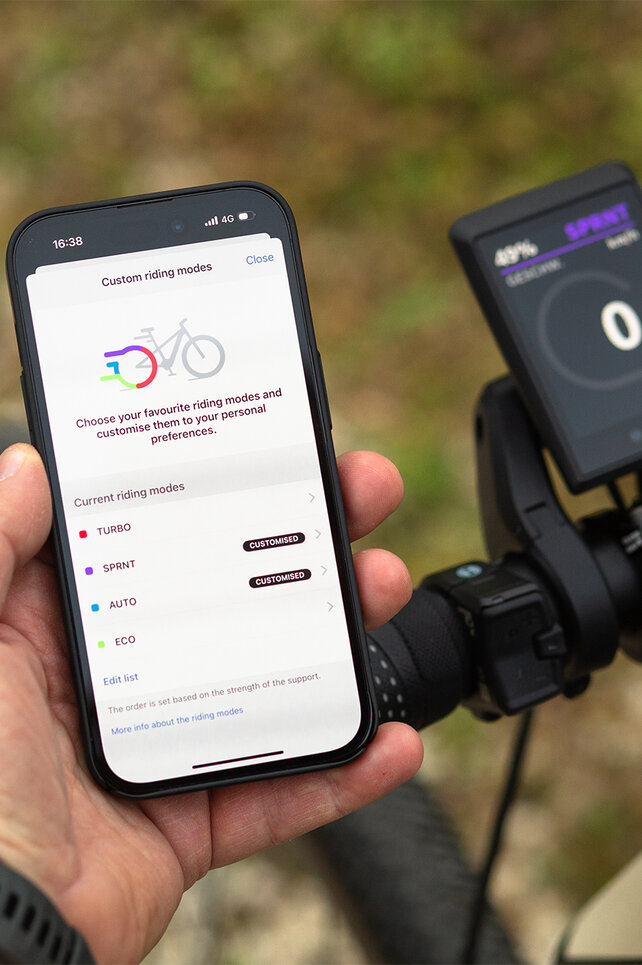 Close-up of a handlebar with Kiox 500 and a smartphone, where you can customize the riding modes.