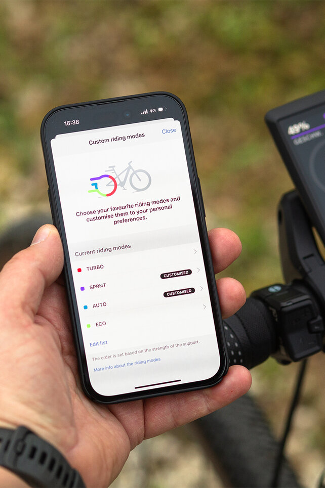 Close-up of a handlebar with Kiox 500 and a smartphone, where you can customize the riding modes.