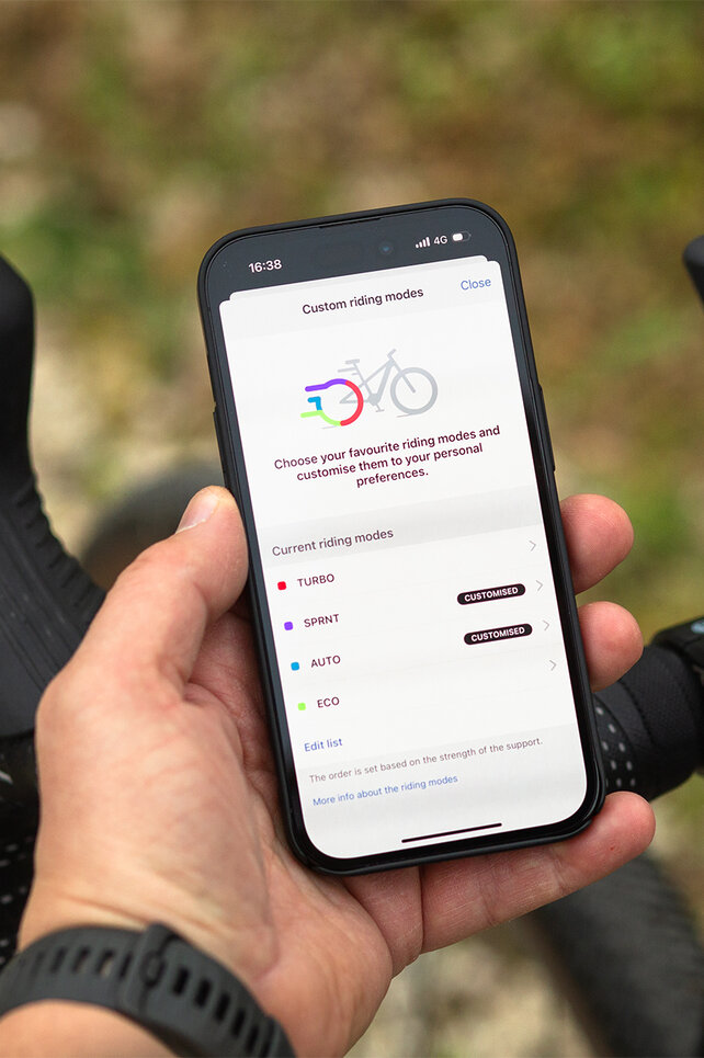 Close-up of a handlebar with Kiox 500 and a smartphone, where you can customize the riding modes.