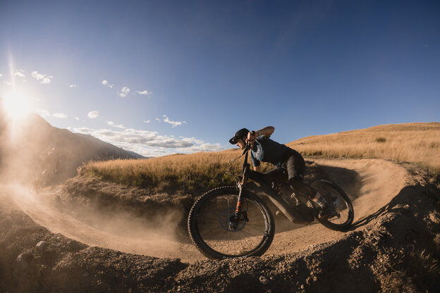 An eMountain bike rider rides along a sandy path, with the sun shining brightly into the camera.