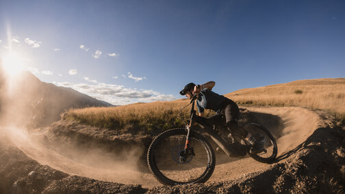 An eMountain bike rider rides along a sandy path, with the sun shining brightly into the camera.
