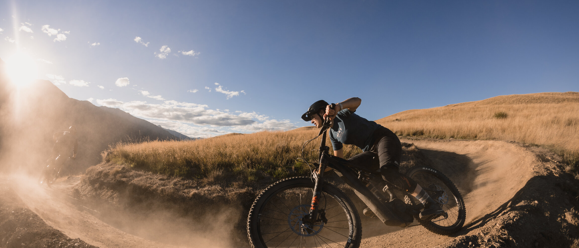 An eMountain bike rider rides along a sandy path, with the sun shining brightly into the camera.