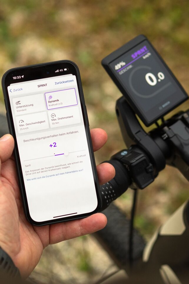 Blick über die Schulter einer Person, die ein Smartphone hält und in der eBike Flow App die Leistungsparameter einstellt.
