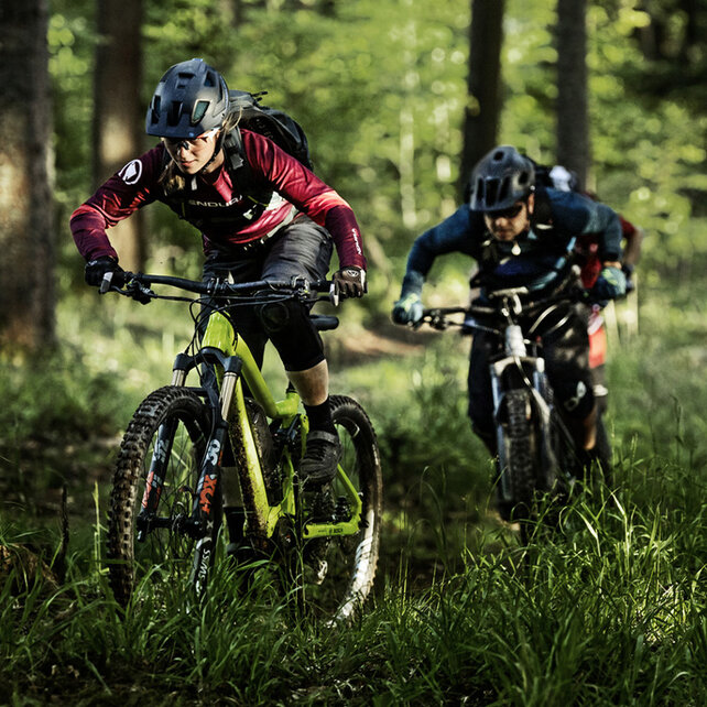 Deux VTT à assistance électrique utilisateur nan traversent les hautes herbes dans une forêt.