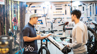 Mechanic & Customer talking in front of Bike and holding brochure