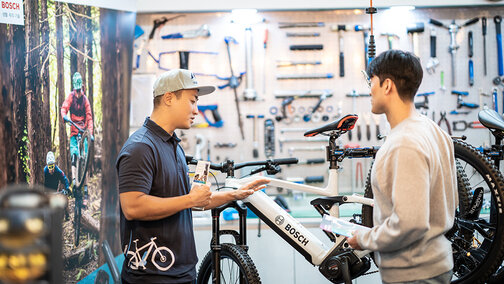 Mechanic & Customer talking in front of Bike and holding brochure