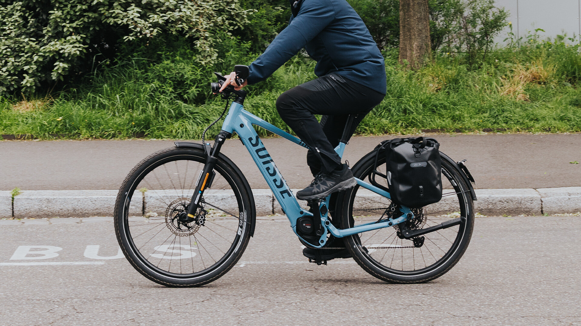 A man rides his eBike quickly down a street in a residential neighborhood.
