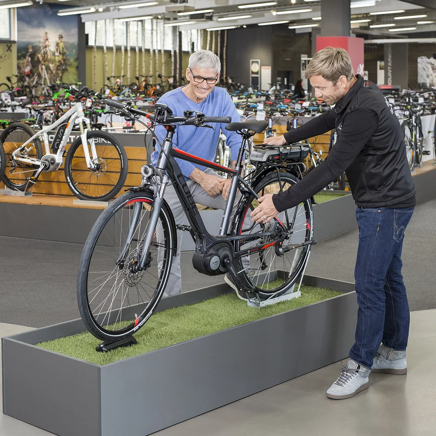 Ein Bosch eBike Berater steht mit einem Mann im Fahrradladen vor einem Ausstellungsfahrrad und erklärt ihm dieses.