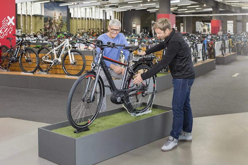 Ein Bosch eBike Berater steht mit einem Mann im Fahrradladen vor einem Ausstellungsfahrrad und erklärt ihm dieses.
