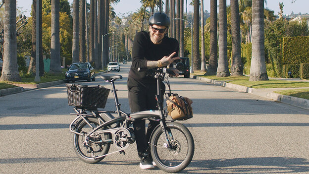 Bob Harper stands in the middle of a street, posing with his eBike.