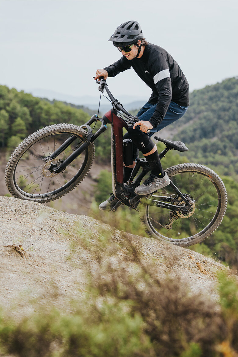 Ein Mann fährt lächelnd auf seinem eMTB durch steiles Gelände in der Natur.