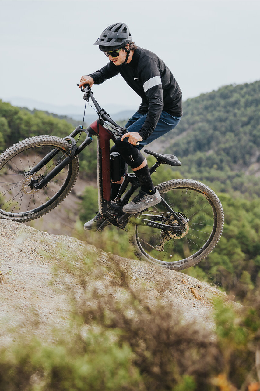 Ein Mann fährt lächelnd auf seinem eMTB durch steiles Gelände in der Natur.