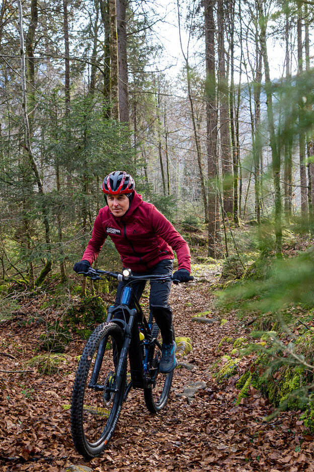 Viktor Röthlin conduit son VAE sur un chemin étroit à travers la forêt.