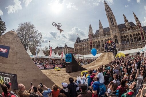 An audience watches extreme bike rider in the air off of a ramp