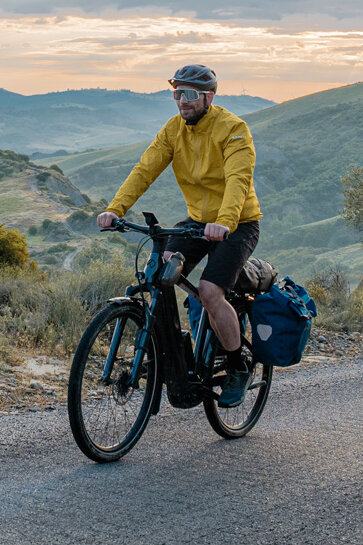 Een vrouw en een man fietsen op een weg met hun eTrekking-bikes, met een uitgestrekt landschap op de achtergrond.