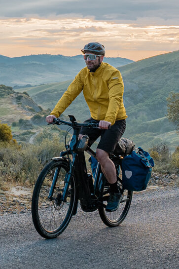 En kvinde og en mand cykler på deres eTrekking-cykler ad en vej med storslået landskab i baggrunden.