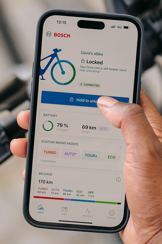 Jezdec na elektrokole drží v ruce svůj smartphone a pomocí aplikace eBike Flow odemyká své eBike.