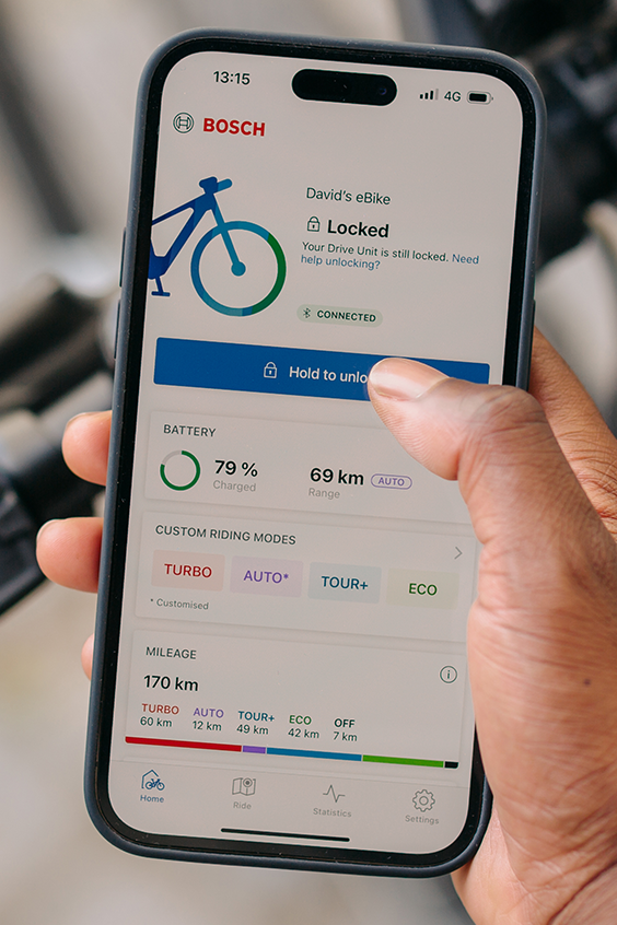 A rider holds his phone in his hand and uses the eBike Flow app to unlock his eBike.