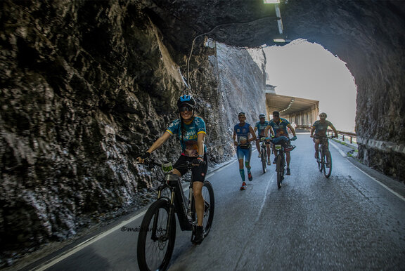Un gruppo di ciclisti di eBike attraversa un tunnel nella roccia.