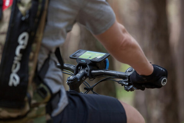 Bildausschnitt, der das COBI.Bike Display am Lenker eines eMountainbike zeigt, das im Wald gefahren wird