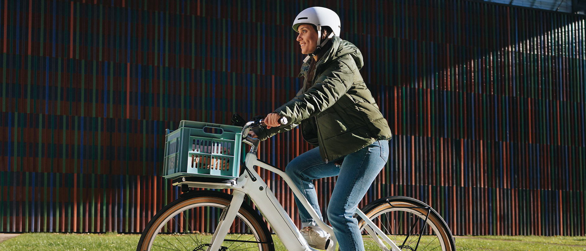 Eine Frau mit Helm fährt mit ihrem weißen eBike eine gepflasterte Straße entlang.