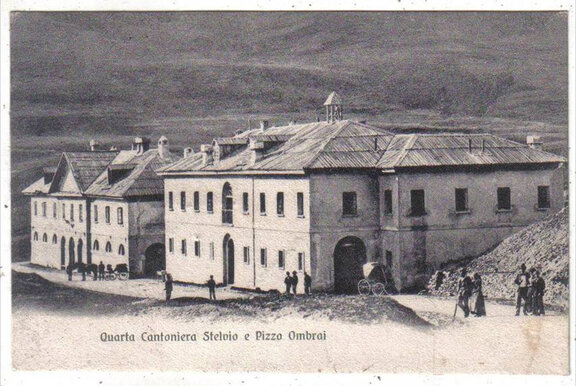 Scatto in bianco e nero di un edificio e di persone che camminano davanti, con la didascalia "Quarta Cantoniera Stelvio e Pizzo Ombrai".