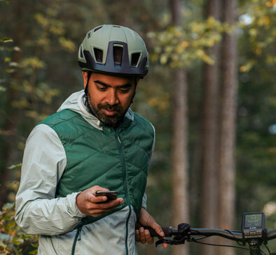 Ein eBiker mit Helm benutzt sein Smartphone.