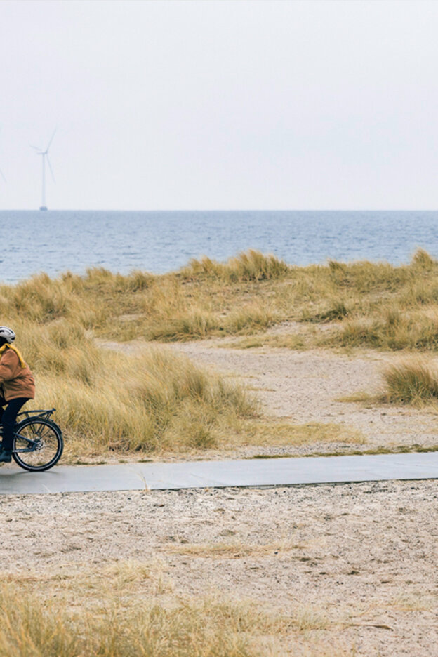 Frau fährt mit einem eCargo Bike entlang der Küste in Kopenhagen.