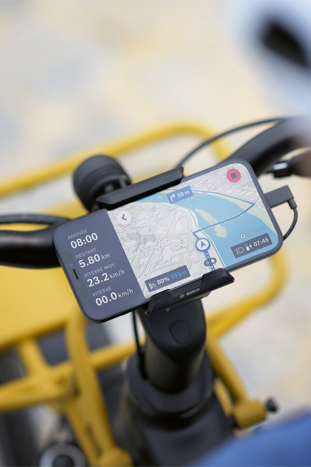 Le smartphone est fixé à une support sur le guidon du vélo et est utilisé comme VAE écran à la navigation, affiche des informations sur l’itinéraire et des indications de navigation.