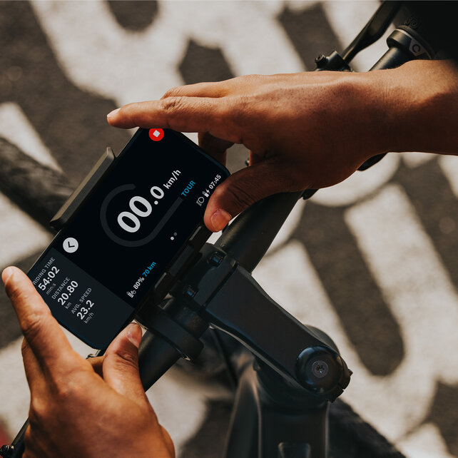 A person attaches his phone to a bicycle handlebar.