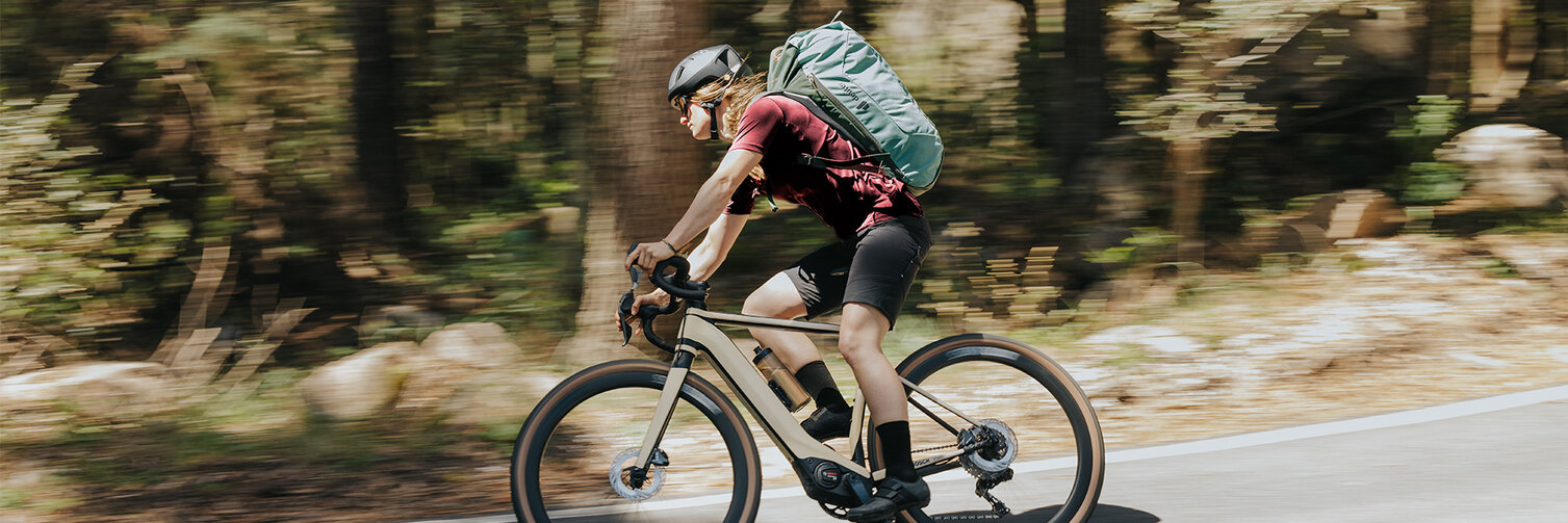 EBikerin rides her Gravel eBike quickly around a curve.