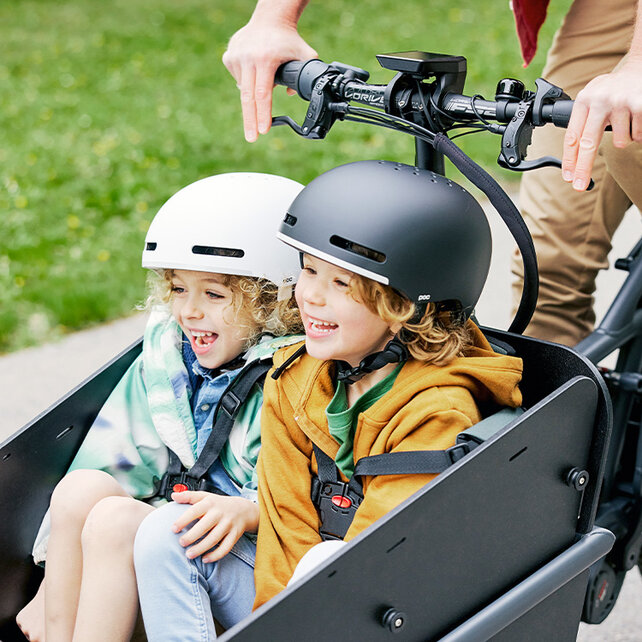Due bambini ridono mentre sono seduti nel cesto carico di un eCargo Bike.