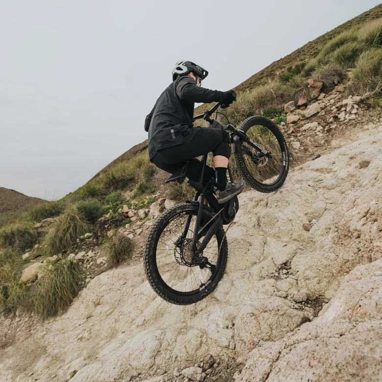Ein eMountainbiker erklimmt einen extrem steilen und felsigen Hang. Er verlagert sein Gewicht nach vorne, um die anspruchsvolle Steigung zu meistern.