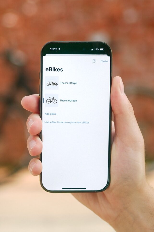 Una persona tiene in mano uno smartphone su cui è possibile visualizzare un elenco delle proprie eBike nell'app eBike Flow.