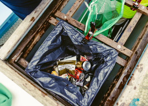 Blikafval en plastic afval liggen naast elkaar in vuilnisbakken op een boot.