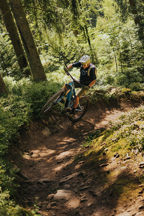 An eBiker performing a wheelie around a curve in a forest.