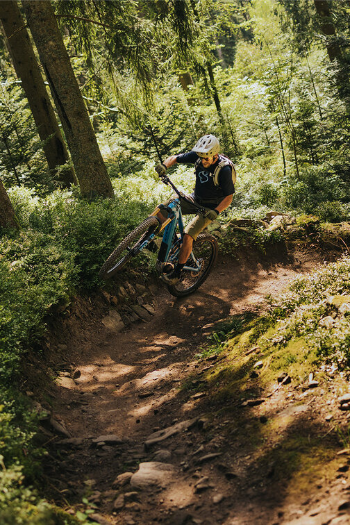 An eBiker performing a wheelie around a curve in a forest.