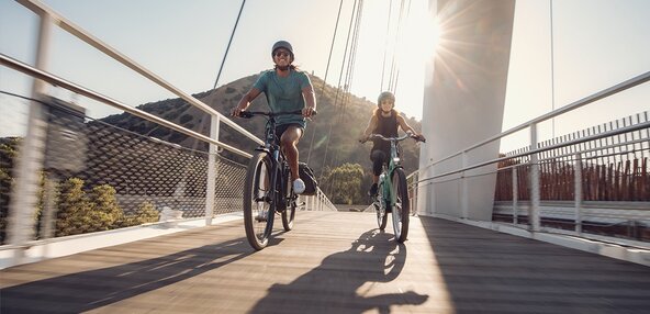 Två elcyklister på en bro 