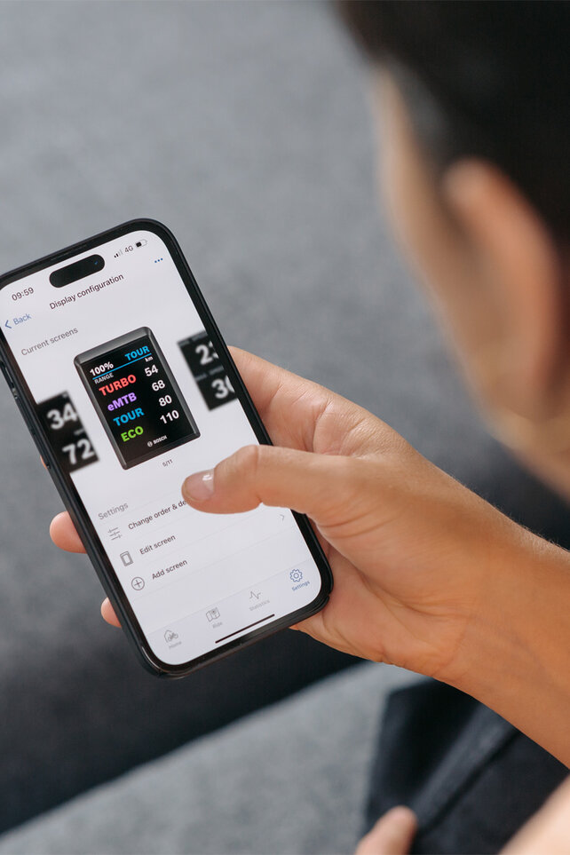 The man configures his personal display in the eBike Flow app on his smartphone.