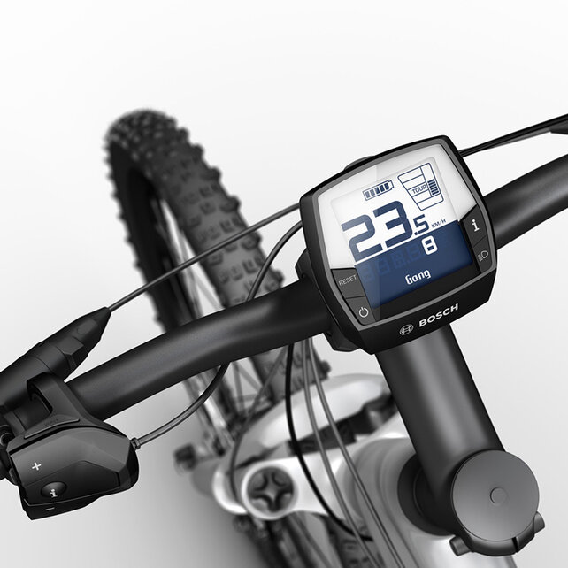 Ein Intuvia Display befestigt an dem Lenker eines silber schwarzen eMountainbikes. Das Display zeigt die Geschwindigkeit, den Gang, die Batterieanzeige und den Fahrmodus an.