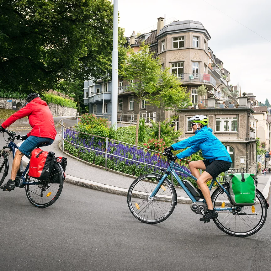 Dos ciclistas de eBike suben por una empinada calle de la ciudad en sus eBikes.